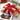 Three gift boxes stacked with a red ribbon and assortment of chocolates on a plate in front on a marble surface