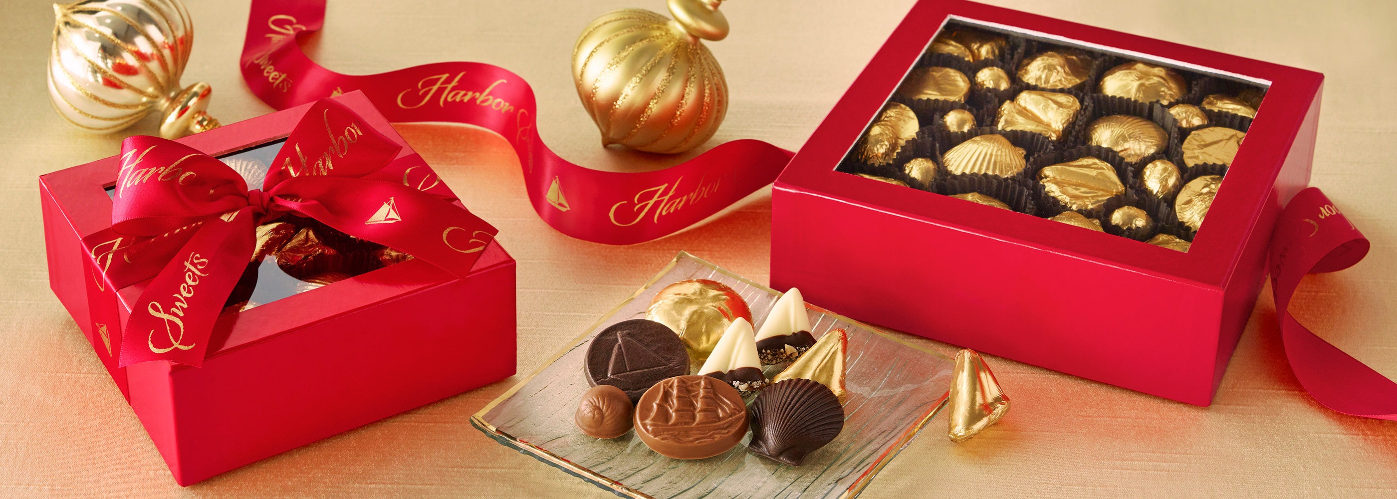 Red gift box with chocolates and a gold ribbon on a beige surface